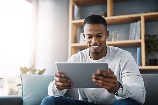 young man sitting on couch looking at a tablet